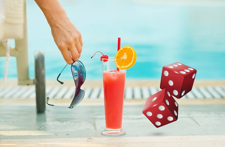 A guest sits next to the pool drinking a cocktail.