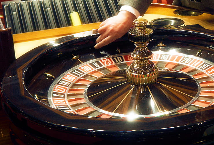 A dealer tossing a roulette ball on the wheel.