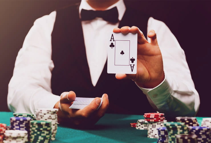 A casino dealer holding an ace of clubs.