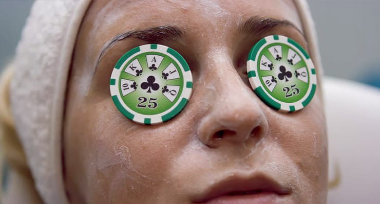 A woman enjoying a spa with cucumber styled poker chips over her eyes.